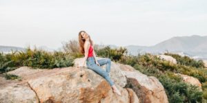 woman sitting on rock next to bushes