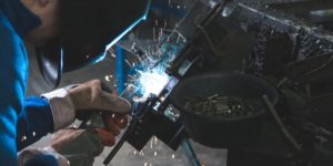 man welding a black metal