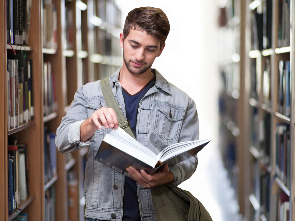 Eine Person, die in einer Bibliothek in Buch liest